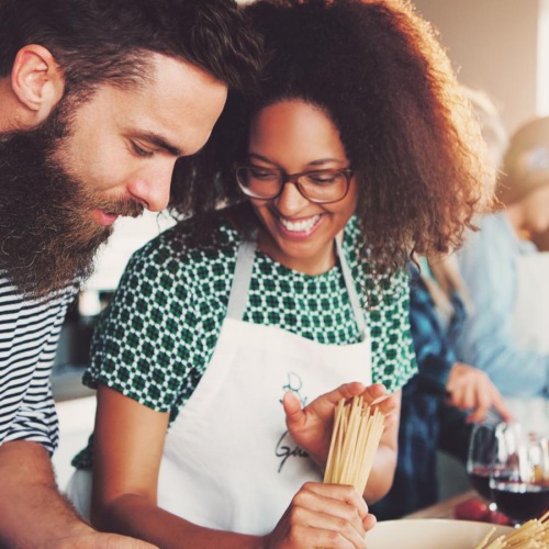 a man and woman smiling making pasta