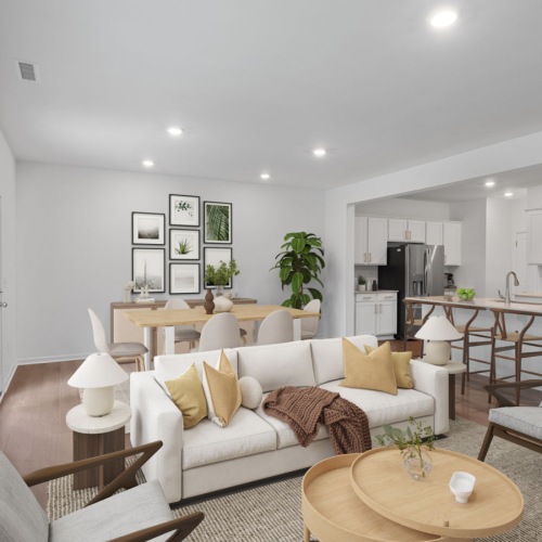 a living room with a kitchen with white cabinets beyond it