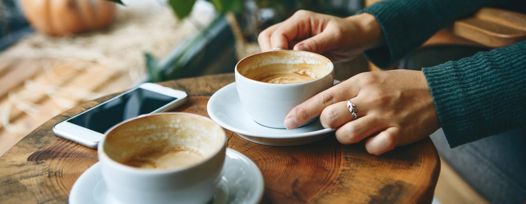 a person holding a phone and a cup of coffee