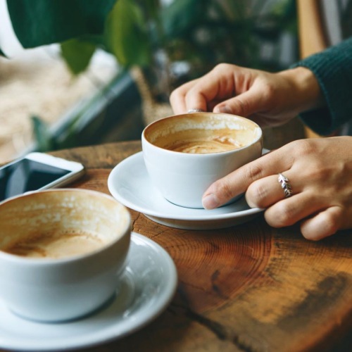 a person holding a phone and a cup of coffee